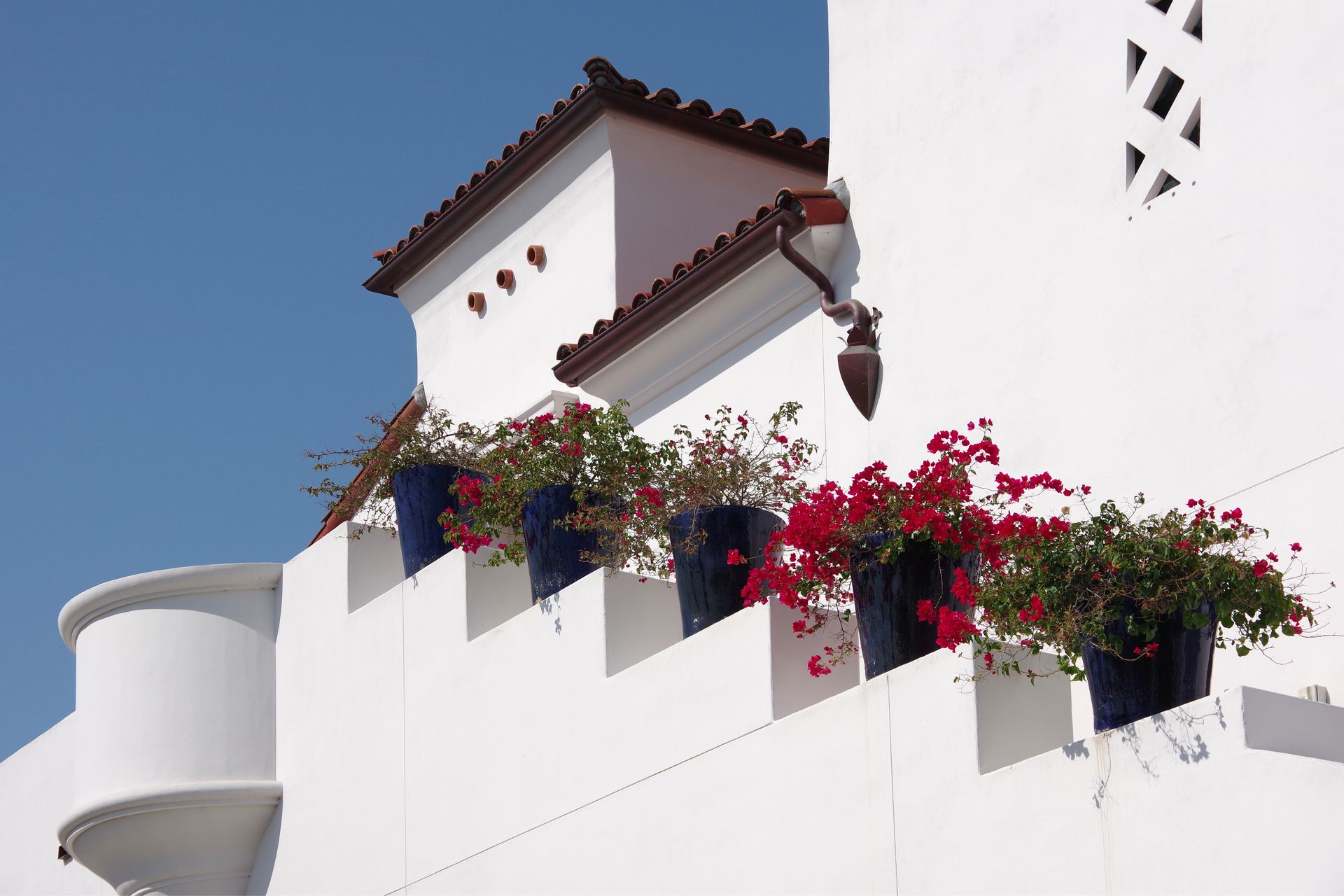 White stucco architecture with a tile roof and red bougainvillea.